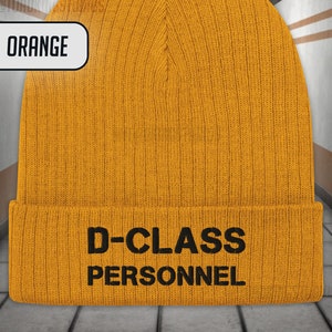 May include: Orange knitted beanie with the text "D-CLASS PERSONNEL" in black.