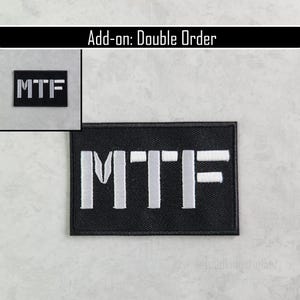 K&ouml;nnte beinhalten: Schwarzer rechteckiger Aufn&auml;her mit den Buchstaben "MTF" in Wei&szlig; gestickt. Der Aufn&auml;her wird vor einem hellgrauen Hintergrund gezeigt. Der Text "Add-on: Double Order" steht oben.