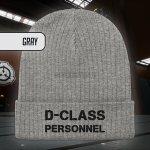 May include: Grey knitted beanie with the text "D-CLASS PERSONNEL" in black.