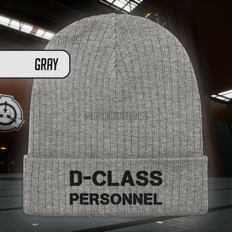 May include: Grey knitted beanie with the text "D-CLASS PERSONNEL" in black.
