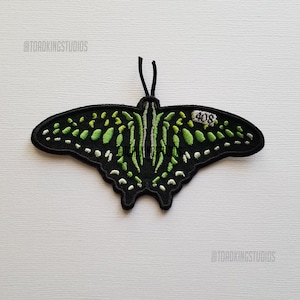 May include: Black and green embroidered butterfly patch with a white tag that says "408".