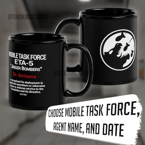 Puede incluir: Dos tazas de cerámica negras. Una taza presenta el texto: "MOBILE TASK FORCE ETA-5 'JAEGER BOMBERS' Dr. Serizawa" y una descripción. La otra taza tiene un gráfico blanco de un monstruo y bombas. Texto en la imagen: "CHOOSE MOBILE TASK FORCE, AGENT NAME, AND DATE."