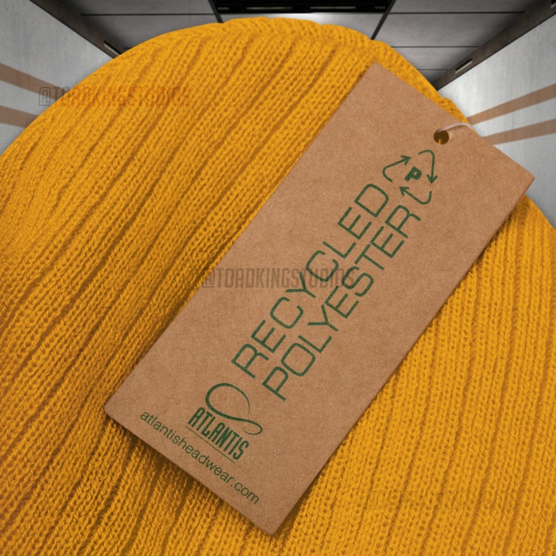 May include: A yellow knitted beanie with a brown tag that reads "Recycled Polyester" and has the logo "Atlantis atlantisheadwear.com".
