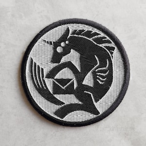 Könnte beinhalten: Runder, gestickter Aufnäher mit einem schwarzen, einhornartigen Wesen, das einen Umschlag hält. Das Design befindet sich auf einem hellgrauen Hintergrund innerhalb eines schwarzen Kreises. Der Aufnäher hat ein detailliertes, strukturiertes Aussehen.