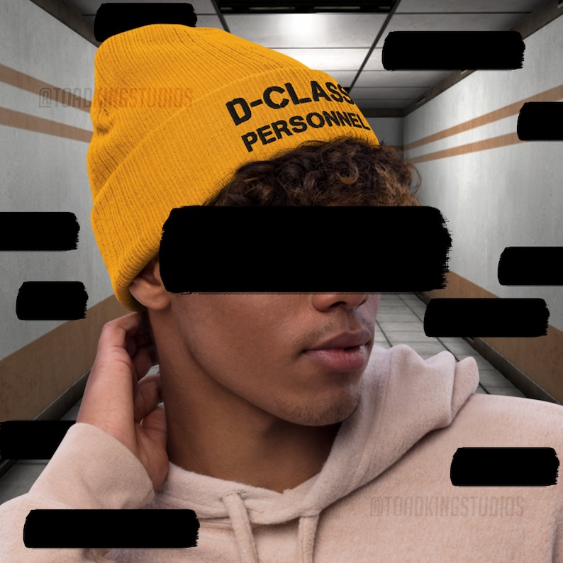 May include: A yellow beanie with the text "D-CLASS PERSONNEL" in black lettering.