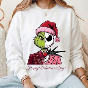 May include: White sweatshirt featuring a split design of the Grinch and Jack Skellington wearing a Santa hat and a suit. The Grinch side is green, and the Jack Skellington side is black and white. The text "Happy Valentine's Day!" is printed at the bottom.