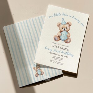 May include: A light beige birthday invitation with a watercolor illustration of a teddy bear holding a number one balloon. The text reads "our little bear is turning one" and "William's beary first birthday". The envelope has blue and white stripes.