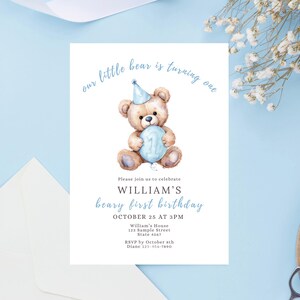 May include: A birthday invitation featuring a watercolor illustration of a teddy bear holding a blue balloon with the number one. The text reads "our little bear is turning one" and "William's beary first birthday".
