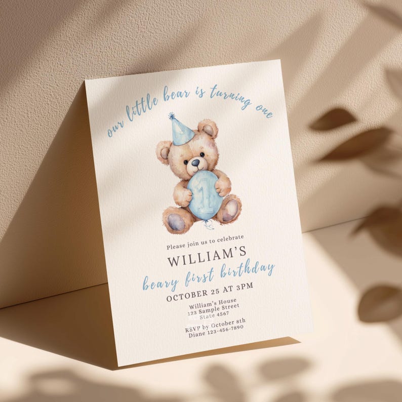 May include: A light beige birthday invitation with a watercolor illustration of a teddy bear wearing a party hat and holding a blue balloon with the number one. The invitation text reads "our little bear is turning one" and details for William's first birthday.