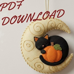 Peut inclure: Décoration d'Halloween en feutre représentant un chat noir dormant sur une citrouille orange nichée dans un croissant de lune crème. La lune est décorée de coutures en spirale et le texte "PDF DOWNLOAD" est en haut à gauche.