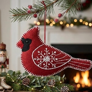 May include: A red felt cardinal bird decoration with white stitching and a snowflake design. The bird has a black beak and eye, and is suspended from a red string. The ornament is part of a festive display.