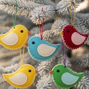Peut inclure: Ornements d'oiseaux en feutre jaune, bleu, rouge et vert, chacun avec un ventre blanc contrastant et un bec orange. Les oiseaux sont cousus avec du fil blanc et suspendus à des cordes colorées, parfaits pour les décorations de fêtes.