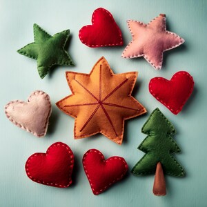 Può includere: Una collezione di ornamenti in feltro fatti a mano in varie forme, tra cui stelle, cuori e un albero di Natale. Gli ornamenti sono in tonalità di rosso, verde, rosa e arancione, con dettagli di cucitura bianchi. Lo sfondo è azzurro.