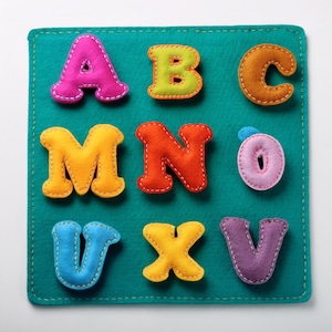 May include: A teal felt board with colorful, stitched felt letters. The letters include A, B, C, M, N, O, U, X, and V. Each letter is a different color, such as pink, orange, yellow, and blue, with contrasting stitching.