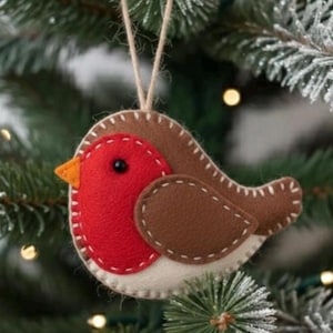 Può includere: Ornamento natalizio fatto a mano a forma di pettirosso. L'uccello presenta un petto rosso, ali marroni e un corpo color crema, con un becco arancione. L'ornamento è appeso a uno spago di spago naturale.