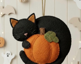 May include: A black cat ornament with orange ears and a pink nose, curled around an orange pumpkin. The cat is sleeping, and the pumpkin has a green leaf and brown stem. A gold string is attached for hanging. Halloween decor.