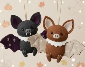 May include: Two felt bat ornaments hanging by gold strings. One bat is dark gray with purple inner wings and white fangs, while the other is brown with beige inner wings. Both feature white scalloped collars and embroidered white star accents.