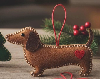 May include: A brown felt dachshund ornament with a red heart and white stitched details. The dog has a red hanging loop and is set against a blurred background with greenery and red berries. A red heart ornament is in the foreground.