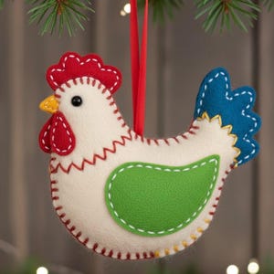 Könnte beinhalten: Handgefertigter Hahn-Ornament aus Filz mit rotem Kamm und Kehllappen, grünem Flügel und blauem Schwanz. Das Ornament ist mit rotem, weißem und gelbem Faden genäht und hängt an einem roten Band. Diese festliche Dekoration ist perfekt für Weihnachten oder Bauernhausdekor.