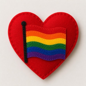 May include: A red felt heart with a rainbow flag design. The flag features horizontal stripes in the colors of the rainbow. The flag is attached to a black pole. The heart is stitched around the edges.
