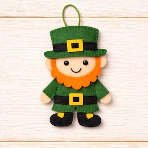May include: A felt leprechaun decoration with a green hat, jacket, and trousers. The leprechaun has a bright orange beard, black shoes, and a yellow buckle on his hat and belt. A green string is attached for hanging.