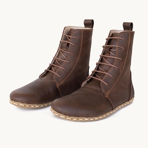 May include: A pair of brown leather lace-up boots. The boots feature a rounded toe, stitched soles, and a pull tab at the ankle. The brown laces complement the leather, which has a slightly worn look. The boots are approximately 20 cm high.