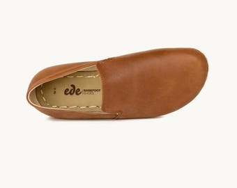 May include: A single brown leather slip-on shoe with a rounded toe. The shoe has a stitched sole and the brand name "ede BAREFOOT SHOES" is visible. The shoe is a size W6.