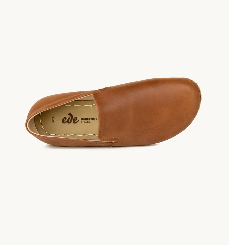 May include: A single brown leather slip-on shoe with a rounded toe. The shoe has a stitched sole and the brand name "ede BAREFOOT SHOES" is visible. The shoe is a size W6.