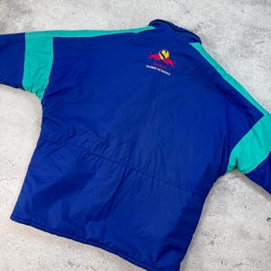 Pu&ograve; includere: Giacca blu e verde acqua con il logo Red Bull Sauber Petronas sul retro. La giacca ha un corpo blu con accenti verde acqua sulle maniche e sulle spalle. Il logo Red Bull &egrave; rosso e giallo.