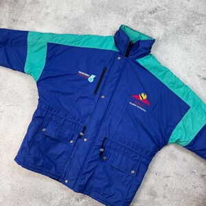 Pu&ograve; includere: Giacca vintage blu e verde acqua con i loghi "PETRONAS" e "SAUBER PETRONAS". La giacca ha un collo alto, una cerniera e due tasche frontali. La giacca &egrave; realizzata in materiale leggero.