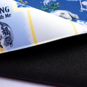 May include: A blue and white patterned mousepad with the text "MAJONG Along With Me" and a koi fish design. The mousepad has a black, textured bottom and a white stitched edge. The design includes yellow stripes.
