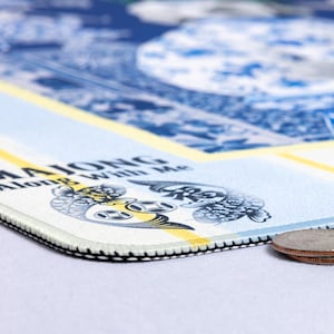 May include: A rectangular mousepad with a blue and white design, featuring a circular pattern and the words "MAJONG Along With Me." The mousepad has a black stitched edge and a yellow stripe. Two coins are visible on the right side.