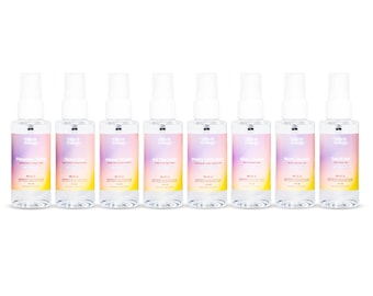 May include: Seven clear spray bottles with white tops and colorful labels. Each label has a different name and a gradient of colors, including pink, yellow, and purple. The bottles are arranged in a row against a white background.