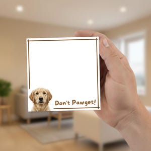 Op de afbeelding: Een witte vierkante notitieblok met een bruine rand en de tekst "Don't Pawget!" in bruin. De afbeelding van een golden retriever staat linksonder.