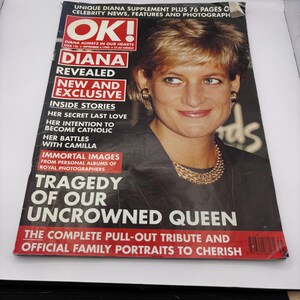 Pode incluir: Uma capa de revista com um retrato de Diana, Princesa de Gales. A capa tem o título "OK!" e manchetes como "Diana Revelada" e "Tragédia da nossa rainha não coroada". A revista está sobre uma superfície branca.