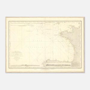 Peut inclure: Une carte nautique ancienne encadrée, représentant des côtes et des routes maritimes détaillées. La carte est imprimée en tons sépia avec des lignes et du texte complexes, encadrée de bois clair. La carte semble être d'une région côtière, possiblement pour la navigation.