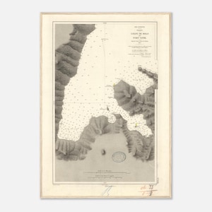 May include: Antique nautical chart of Golfe de Milo, Port Vitil, in a cream-colored frame. The map features detailed illustrations of the coastline, water depths, and navigational markers. The chart is in black and white, with text in French.