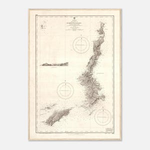 Peut inclure: Une carte marine encadrée intitulée The Island of Scarpanto and Kasos, présentant un relief topographique détaillé, des sondages de profondeur et trois roses des vents. La carte est imprimée en noir sur un fond beige clair avec un cadre en bois.