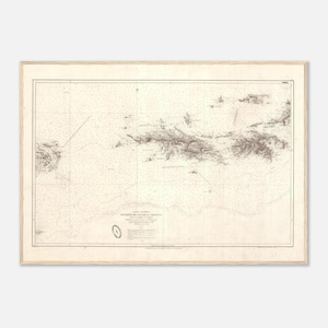 Op de afbeelding: Een ingelijste vintage nautische kaart, getiteld "Carte Oueste de las Islas Virgenes". De kaart, in een houten lijst, toont gedetailleerde kustlijnen, eilanden en zeedieptes. Tekst is zichtbaar aan de onderkant. De kaart is beige en bruin.
