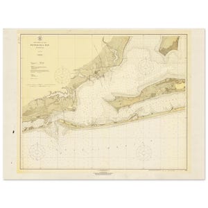 Op de afbeelding: Een vintage nautische kaart van Pensacola Bay, Florida. De kaart toont gedetailleerde kustlijnen, dieptemetingen en navigatiemarkeringen. De kaart is gedrukt in tinten beige, bruin en bruin, met tekst die de naam van de baai en andere geografische details aangeeft.