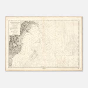 May include: A vintage nautical chart, framed in light wood. The map features detailed lines and text, with a focus on coastal regions. The chart's color palette is primarily cream and gray, giving it a classic, aged appearance. The text is in a foreign language.