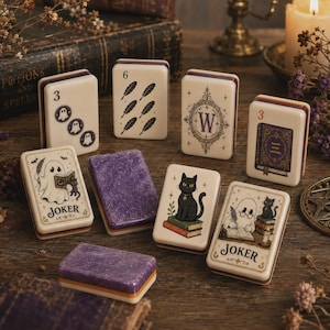 May include: A collection of rectangular game tiles featuring cream-colored surfaces with various illustrations including ghosts, black cats, books, feathers, and the letter W. Two tiles are solid purple with glitter, and two are labeled Joker.
