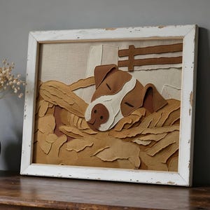 May include: A framed artwork featuring a dog resting in a bed of hay. The dog has brown and white fur, with a brown nose and ears. The artwork is framed in a distressed white wooden frame. The background is a neutral beige.