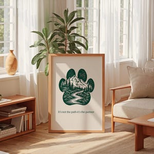 May include: A framed print with a green paw print design, depicting a mountain and forest landscape. The print includes the text "It's not the path-it's the partner". The artwork is in a light wooden frame, ideal for interior decoration.