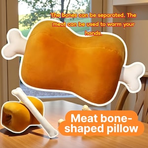 May include: A plush, meat bone-shaped pillow in shades of orange and white. The pillow has a large, rounded shape with two bone-shaped protrusions. Text on the image reads, "The bones can be separated. The meat can be used to warm your hands."
