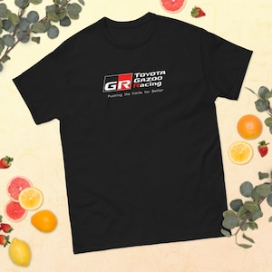 May include: Black t-shirt featuring the Toyota Gazoo Racing logo in white, red, and black. The text "Pushing the limits for Better" is below the logo. The shirt is a short-sleeved crew neck.