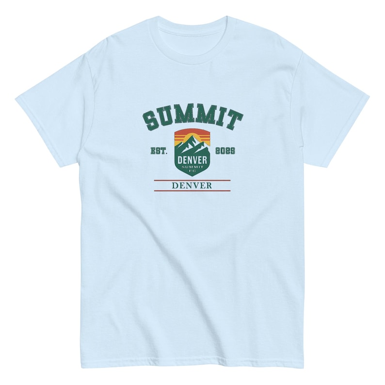 K&ouml;nnte beinhalten: Hellblaues T-Shirt mit einem grafischen Design. Das Design zeigt das Wort "SUMMIT" in gr&uuml;nem, bogenf&ouml;rmigem Text &uuml;ber einer Berg- und Sonnenuntergangsgrafik. Darunter steht "DENVER SUMMIT CO." und "8088". Das Wort "DENVER" ist rot gedruckt.