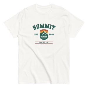 K&ouml;nnte beinhalten: Wei&szlig;es T-Shirt mit einem gr&uuml;nen, orangefarbenen und blauen Aufdruck. Der Aufdruck zeigt das Wort "SUMMIT" &uuml;ber einer Berglandschaft und "DENVER" darunter. Der Text "EST. 8088" und "DENVER" sind ebenfalls enthalten.