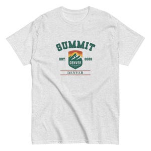 K&ouml;nnte beinhalten: Hellgraues T-Shirt mit einem Bergmotiv. Die Grafik enth&auml;lt das Wort "SUMMIT" in Gr&uuml;n, den Text "DENVER" und "8088" sowie ein Berg- und Sonnenuntergangsdesign. Das T-Shirt besteht aus einem weichen Material.