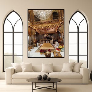 Könnte beinhalten: Ein gerahmtes Foto einer religiösen Stätte mit goldenen und roten Verzierungen. Ein großer Kronleuchter hängt von der Decke. Mehrere Personen sitzen auf dem Boden. Das Foto wird über einem weißen Sofa und einem Couchtisch aus dunklem Holz angezeigt.